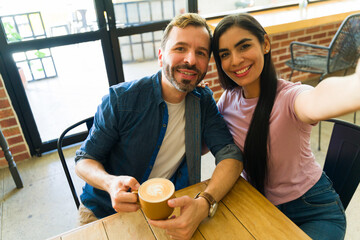Happy couple taking selfie while having coffee at cafe