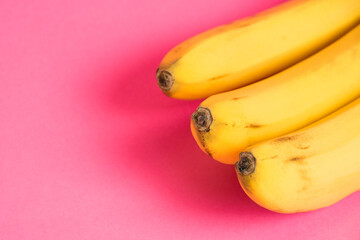 A branch of bananas with spoiled skin on a pink background
