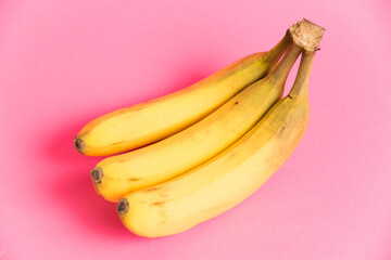 A branch of bananas with spoiled skin on a pink background