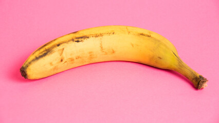 Banana with spoiled skin on pink background. Save the lonely banana