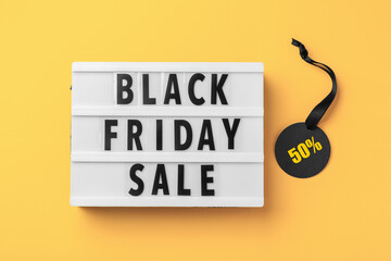 Lightbox with black friday sale word and discount tag with black ribbon on yellow background