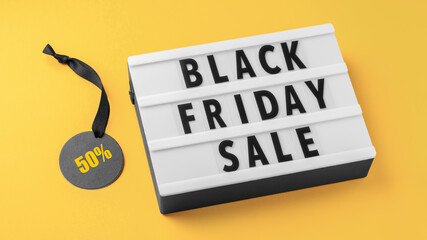 Black friday sale word lightbox with discount tag and black ribbon on yellow background