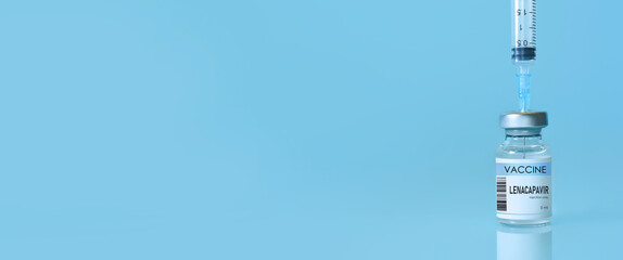 Bottle of Lenacapavir vaccine with syringe on blue background and copy space, illustrating HIV...