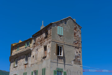 An old, weathered building with crumbling plaster revealing stone and brickwork, and various...