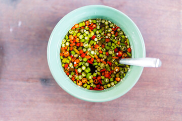 Fish sauce with red and green chili in green bowl. Top view