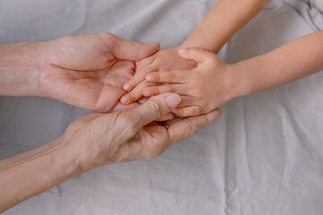 Asian baby hands on grandmother's hand. Connection and sharing moment. Family affection, bonding...
