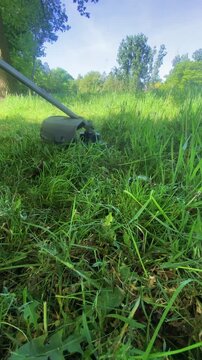 Close Up Of String Trimmer Head Cutting Through Long Green Grass During Professional Garden Maintenance