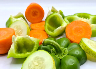 Fresh vegetable salad on white background. fresh sliced vegetables carrot, cucumber, and green bell...