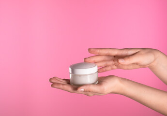 Hand Holding White Cream Jar on Pink Background