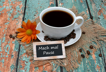 Holzschild mit der Aufschrift „Mach mal Pause“ vor einer Tasse Kaffee.