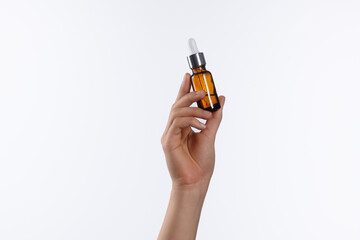 Hand Holding Small Amber Glass Dropper Bottle for Liquid or Oil