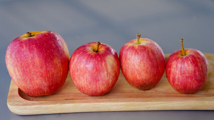 A handful of bright red apples lie on the ground.