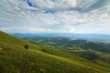A breathtaking view from the hills along the path to Shiljak on mountain Rtanj in Serbia, showcasing lush greenery and dramatic clouds.