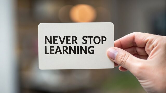 A hand holding a card with the motivational message "Never Stop Learning" against a blurred background.