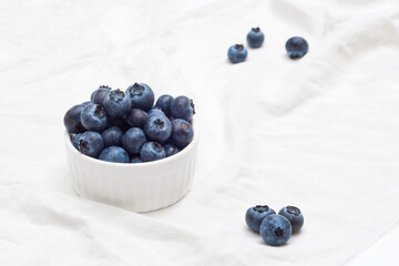 Ripe blueberries in a bowl on white background. Organic fruits, forest berries