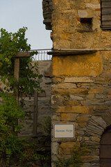 A rustic stone building wall, likely aged, features an engraved date 
