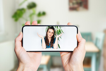 Female hands are holding the phone in the background of the room. The patient communicates with the...