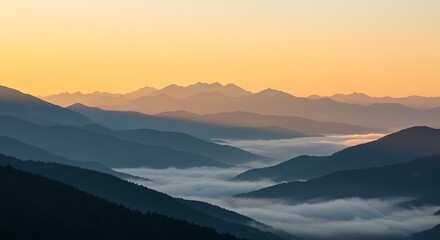 A serene mountain range bathed in the warm glow of the rising sun, with valleys filled with mist.