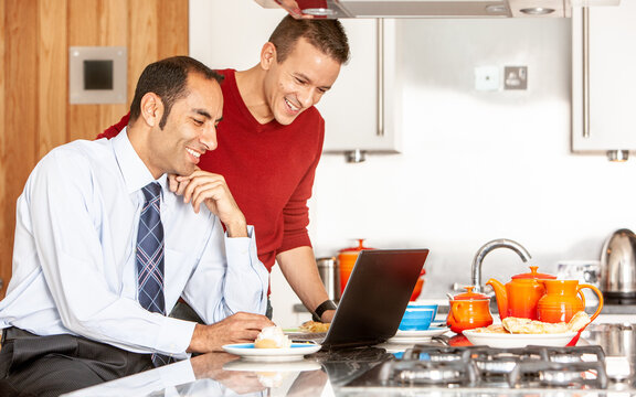 Gay Lifestyle: Facetime Friends. A same sex couple using a laptop computer with bright, relaxed smiles. From a series of related images.