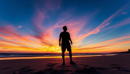 Fototapeta premium Silhouetted figure on beach, vibrant sunset sky, textured sand, peaceful, sky