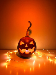 A carved Halloween pumpkin. Jack-o'-lantern glowing with a candle inside on a surface with...