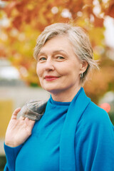 Outdoor autumn close up portrait of beautiful mature woman with grey hair