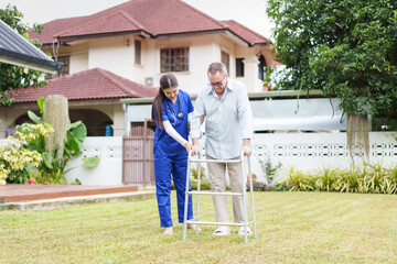 Home caregiver assisting elderly man with walker in garden, supportive and caring atmosphere,...