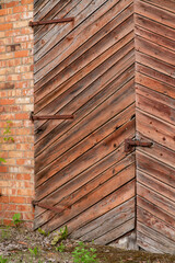 The photo shows a close-up of old wooden gates with diagonal planking set into a brick wall.
