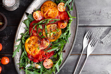 Simple Italian Salad with Tomatoes and Arugula on black wooden background, Italian Food, copy space...