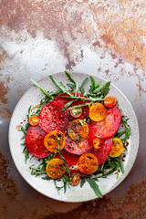 Simple Italian Salad with Tomatoes and Arugula on rusty background, Italian Food, vertical photo with copy space for text