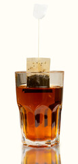 closeup tea bag in a transparent tea cup, black tea in tall glass isolated on white background. 
