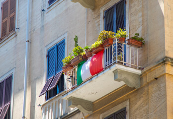 Wooden shutters on the windows. Italian flag and flowers on the Italian open balcony house. La...