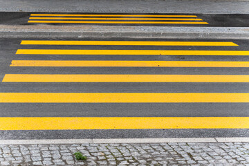 Yellow pedestrian crossing zebra crossing with clear lines on dark asphalt. The focus is on the...