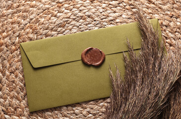 Vintage envelope with wax seal and stamp, dry grass on woven mat, Wedding invitation