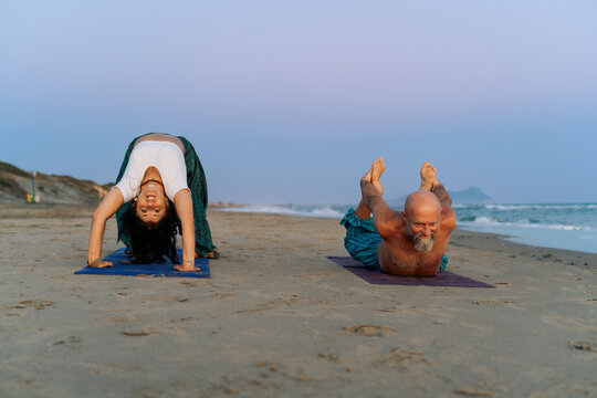 Couple Performing Advanced Yoga Poses on the Beach at Sunset