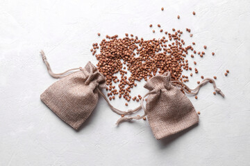 Buckwheat grains in a miniature burlap bags on a white concrete background