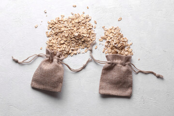 Dry oatmeal in a miniature burlap bags on a white concrete background