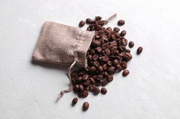 Coffee beans with miniature burlap bag on white concrete background