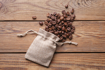 Coffee beans with miniature burlap bags on wooden table