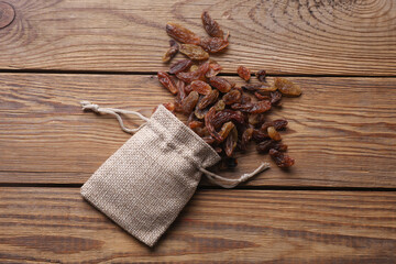 Raisins in miniature burlap bag on wooden table