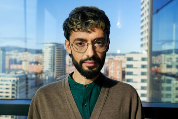 Headshot portrait of a confident man looking at camera seriously in a modern office.