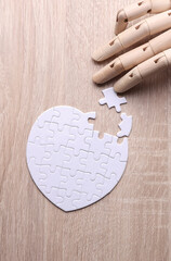 Robotic wooden hand of puppet assembles puzzle on table. Artificial intelligence training concept