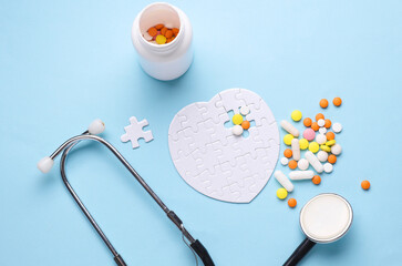Stethoscope, medicines and white puzzle in the shape of heart. Diagnosis and treatment of heart...