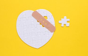 Medical plaster and white puzzle in the shape of a heart. Diagnosis and treatment of heart...
