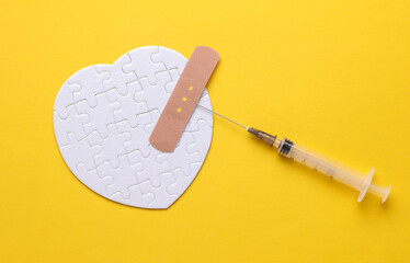 Syringe, patch and white puzzle in the shape of a heart. Diagnosis and treatment of heart diseases....