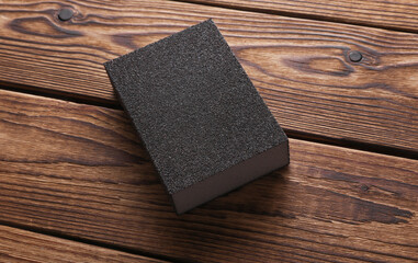 Sanding block on wooden background close up