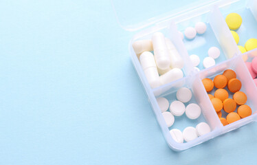 Plastic divider box with pills on blue background