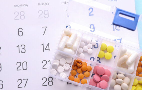 Calendar and Plastic divider box with pills on blue background