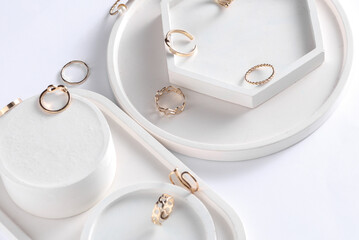 Gold rings of different shapes with plaster trays on white background. Podium showcase for product presentation. Women's jewelry store concept. Creative layout