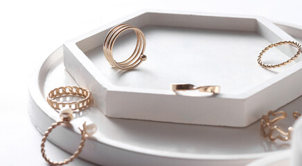 Gold rings of different shapes with plaster trays on white background. Podium showcase for product presentation. Women's jewelry store concept. Creative layout